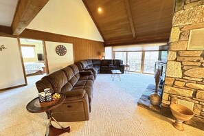 A cozy living room with a sectional sofa, a fireplace, and a stone wall.