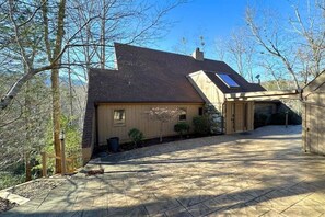 A house with a sloped roof, a covered garage, and a paved driveway. - Tranquility at Rumbling Bald (Lake Lure)