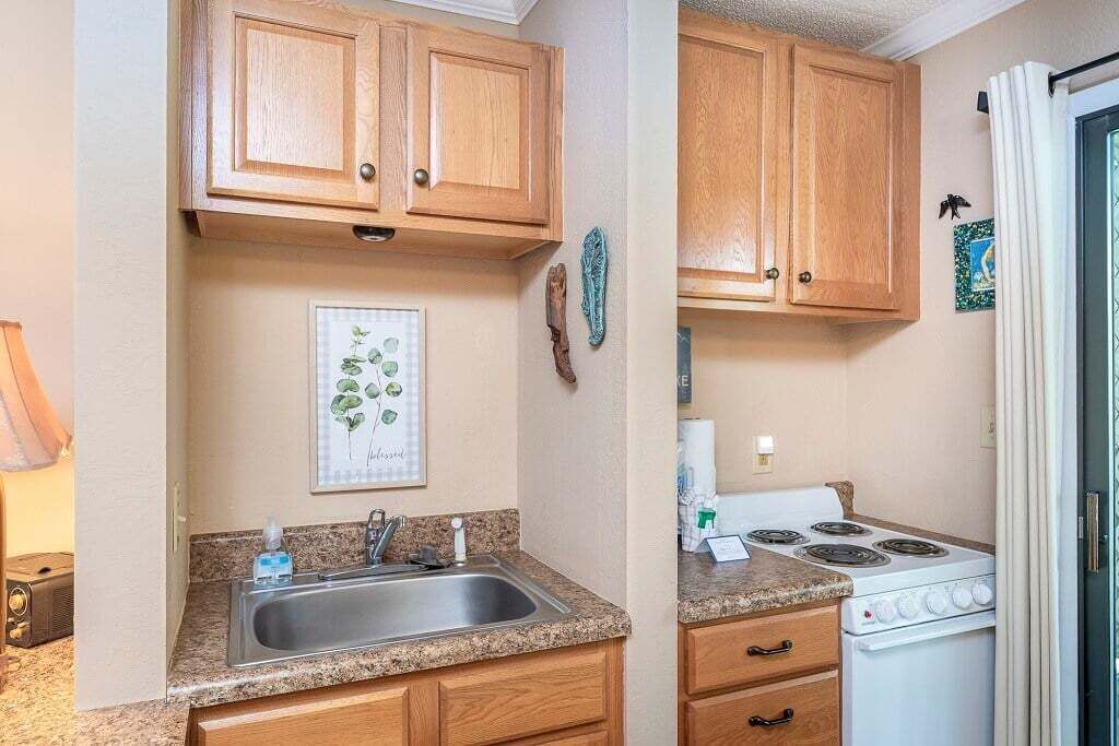 Een compacte keuken met houten kastjes, een granieten aanrechtblad, een spoelbak en een fornuis.
