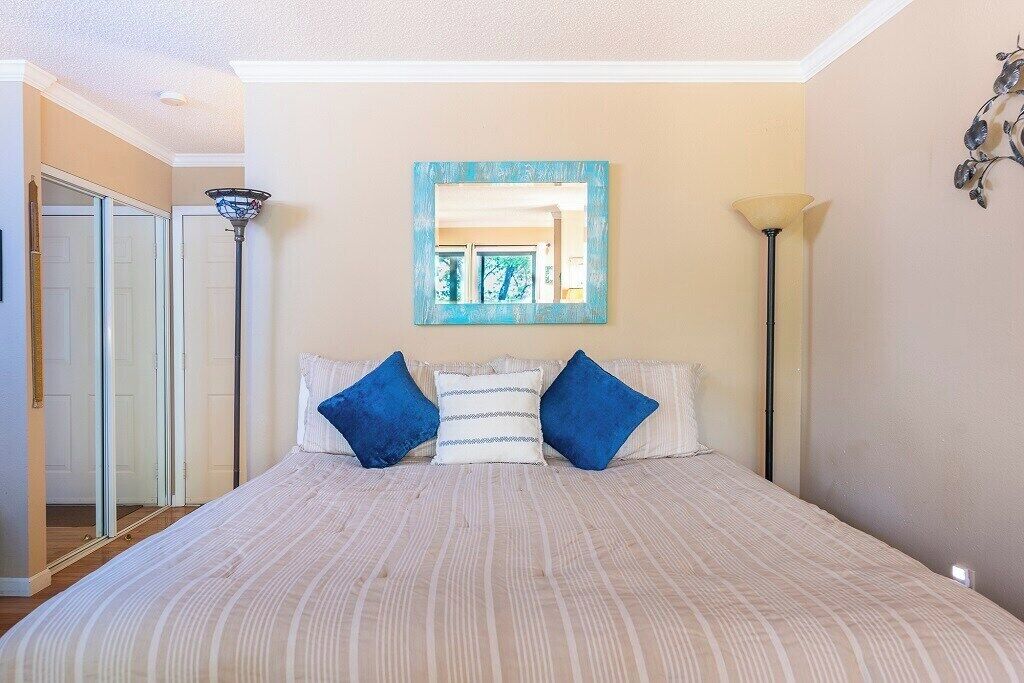 Een slaapkamer met een bed, een spiegel en een lamp.