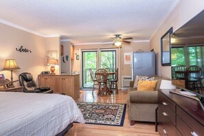 A bedroom with a bed, a desk, a chair, a dresser, a ceiling fan, and a large window. - Apple Valley  57 at Rumbling Bald (Lake Lure)