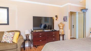 A bedroom with a bed, a dresser, a television, a lamp, and a door.