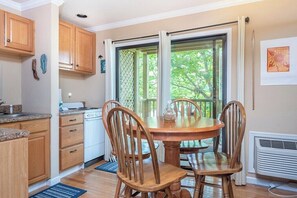 A kitchen with wooden cabinets, a stove, and a dining table with chairs. - Apple Valley  57 at Rumbling Bald (Lake Lure)