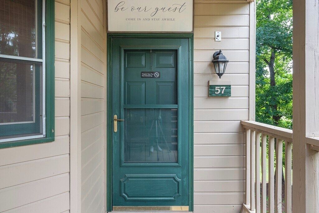 Una puerta verde con un letrero encima que dice 'sean nuestros invitados' y el número 57 en la pared.