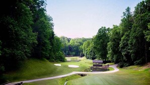 Un campo de golf con un estanque, un puente y un pabellón.