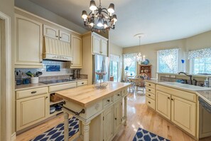 Une cuisine spacieuse dotée d’un îlot central, de meubles en bois et d’un lustre.