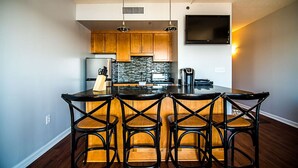 A modern kitchen with a central island, wooden cabinets, and a built-in TV. - WSR-12 Riverfront balcony views. (Wilmington)
