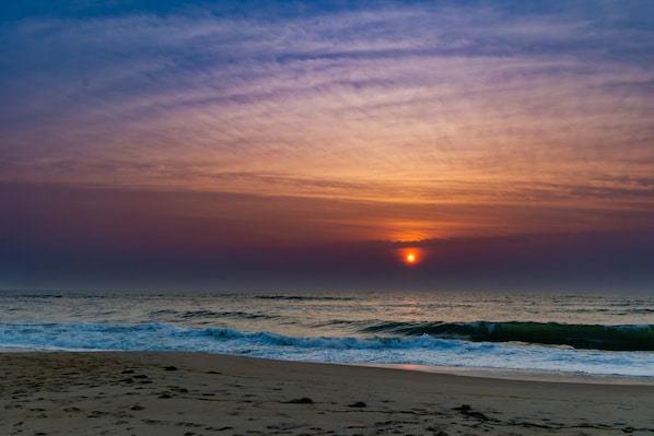 A beach with waves and a sunset.