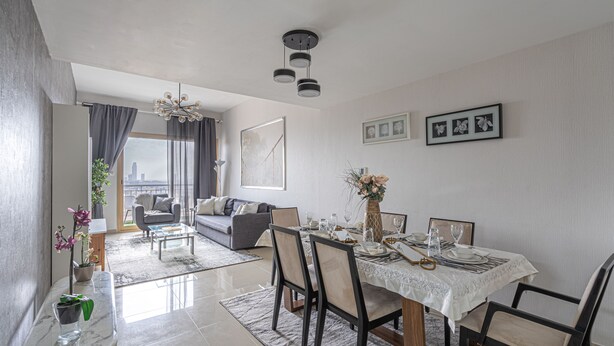 Een moderne eetruimte met een tafel voor vier personen, een bank en uitzicht over de stad.