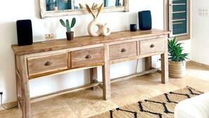 Une console en bois avec des tiroirs, un grand miroir au-dessus et une plante en pot à côté.