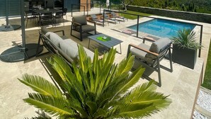 Une terrasse extérieure moderne, dotée d’une piscine, d’un espace salon et offrant une vue sur le paysage environnant.