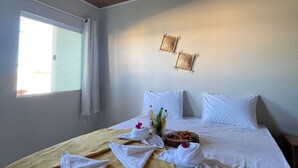 Una habitación de hotel con una cama, una ventana y una lámpara fijada a la pared.