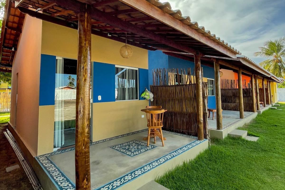 A two-story building with a covered patio area, a small table, and a chair.