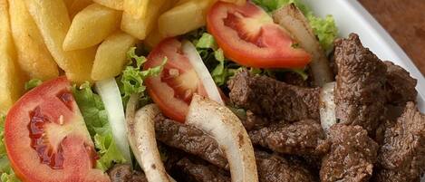 A plate of food with beef, fries, and salad.