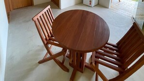 Una habitación con una mesa redonda de madera y cuatro sillas, un refrigerador blanco pequeño y una puerta que da a un espacio exterior.
