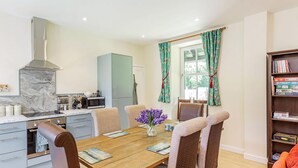 A modern kitchen with a marble backsplash, a built-in oven, and a microwave. There is a dining table with chairs and a vase of flowers.
