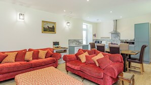 A living room with two red sofas, a wooden coffee table, and a dining area with chairs and a table.