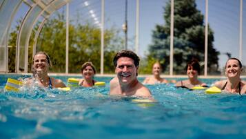 Una piscina con agua cristalina azul, rodeada por un cerramiento de vidrio.