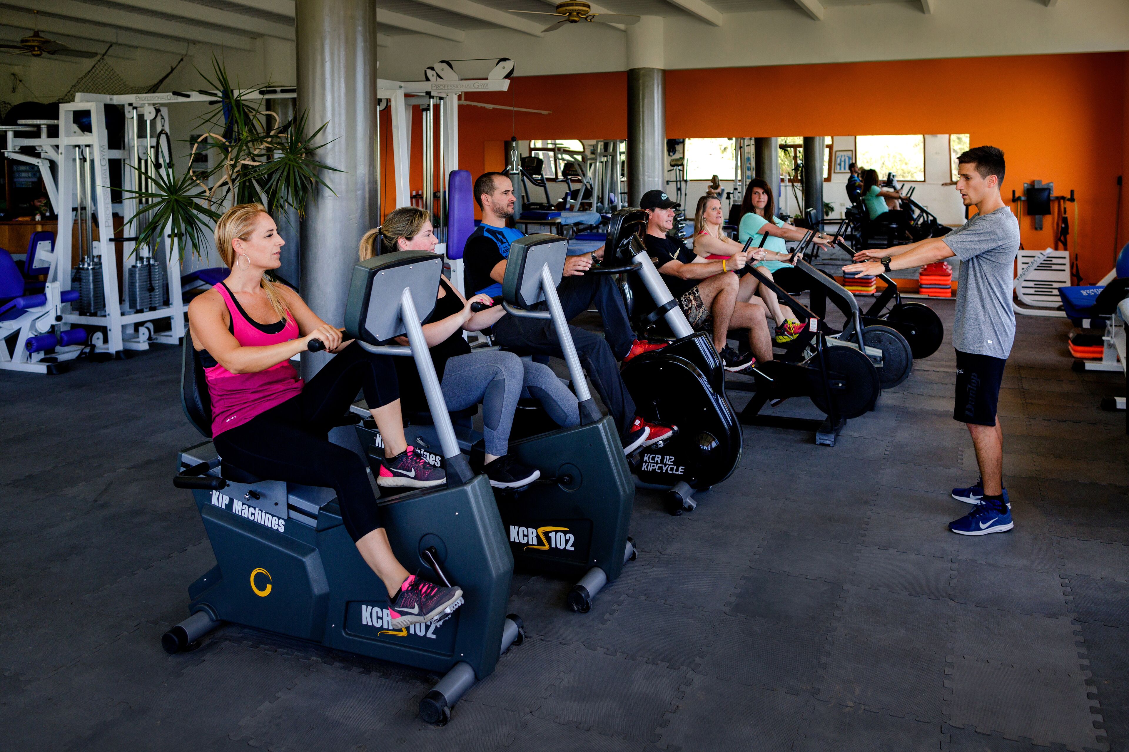 A gym with stationary bikes, weight machines, and a person standing.