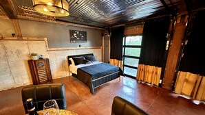 A room with a bed, a table with a bottle and glass, a chair, a radio, and a window with curtains. - Amazing view and location (Springfield)