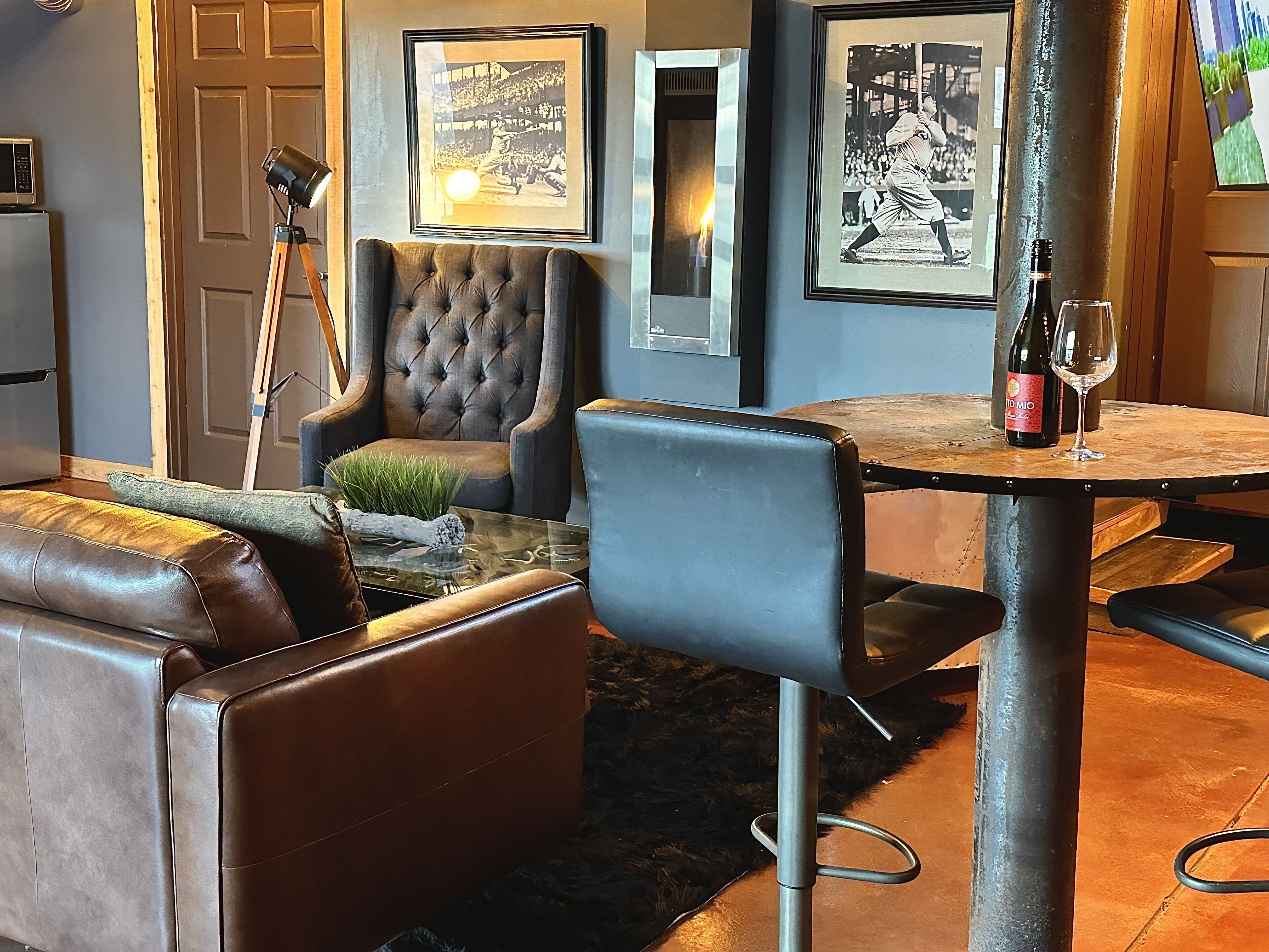 Un salon moderne avec des canapés en cuir, un fauteuil capitonné, une table basse en verre et des photographies en noir et blanc encadrées accrochées au mur.