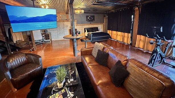A spacious living room with a large flat-screen TV, leather sofas, a coffee table, and a bicycle. - Amazing view and location (Springfield)