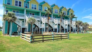 Una hilera de casas de colores frente a la playa, con balcones y escaleras que bajan a la arena.