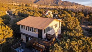 A two-story house with a sloped roof, a deck, and a mountain backdrop. - Skyview Terrace (Saguache County)