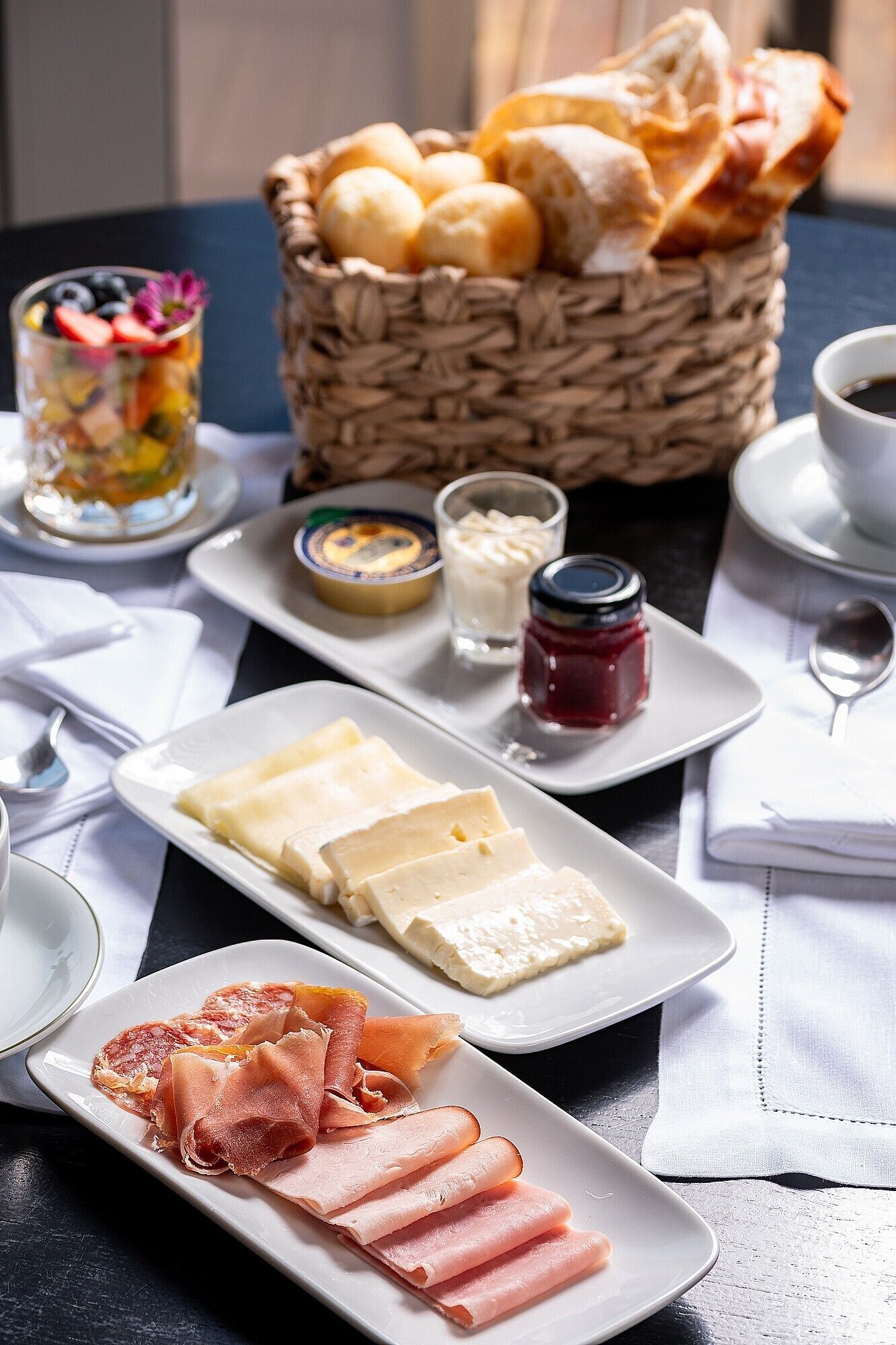 A breakfast setting with various food items including pastries, cheese, and cured meats.