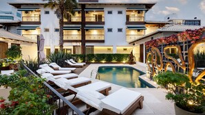 A hotel with a pool, lounge chairs, and a modern building facade. - Villa d'Ozio Hotel e Cucina (Itajai)