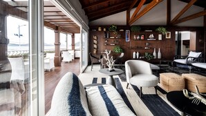 A spacious living area with a high ceiling, wooden beams, a large window, and a view of the outdoors. - Villa d'Ozio Hotel e Cucina (Itajai)