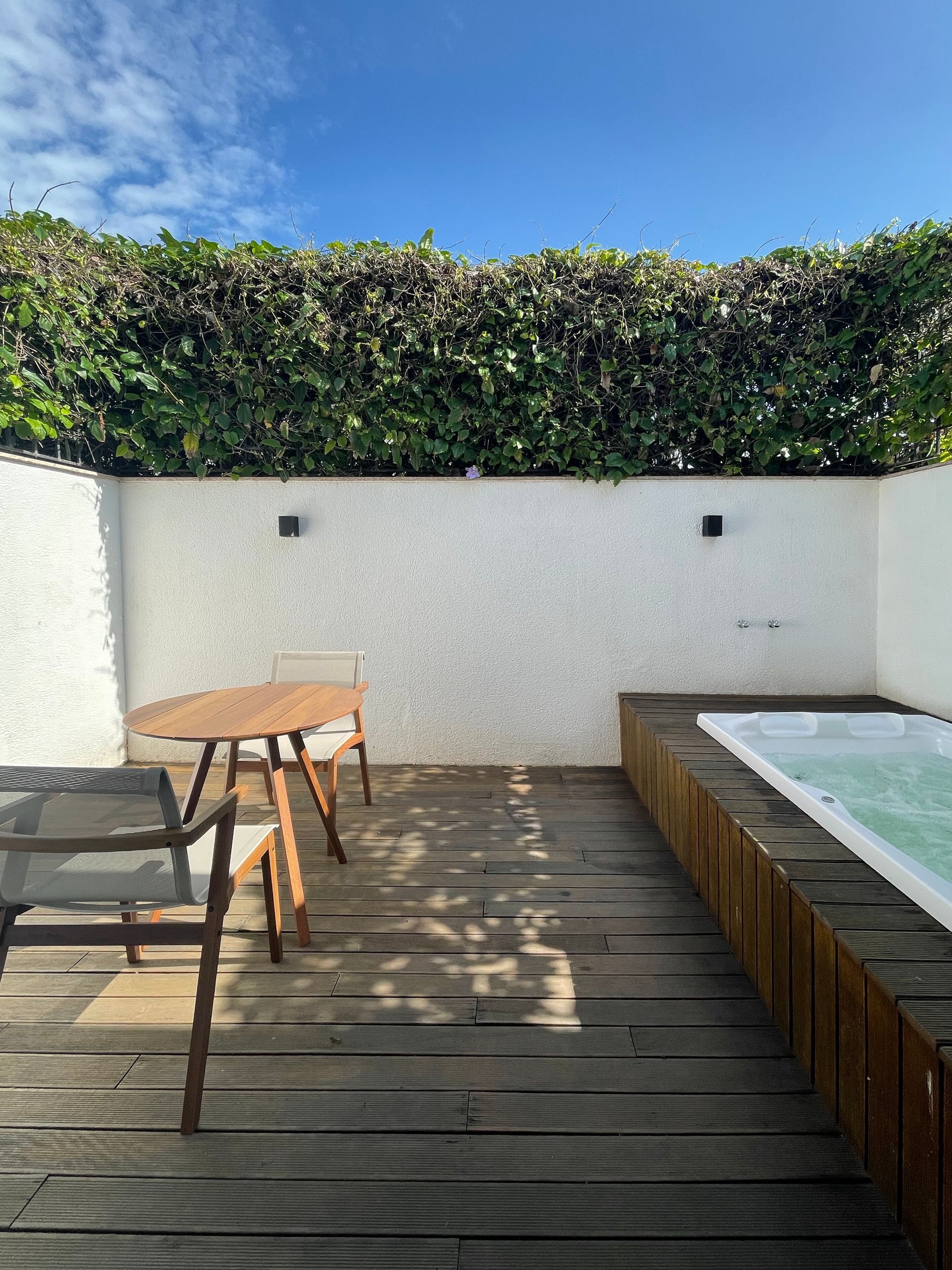 A wooden deck with a hot tub, a table, and chairs.