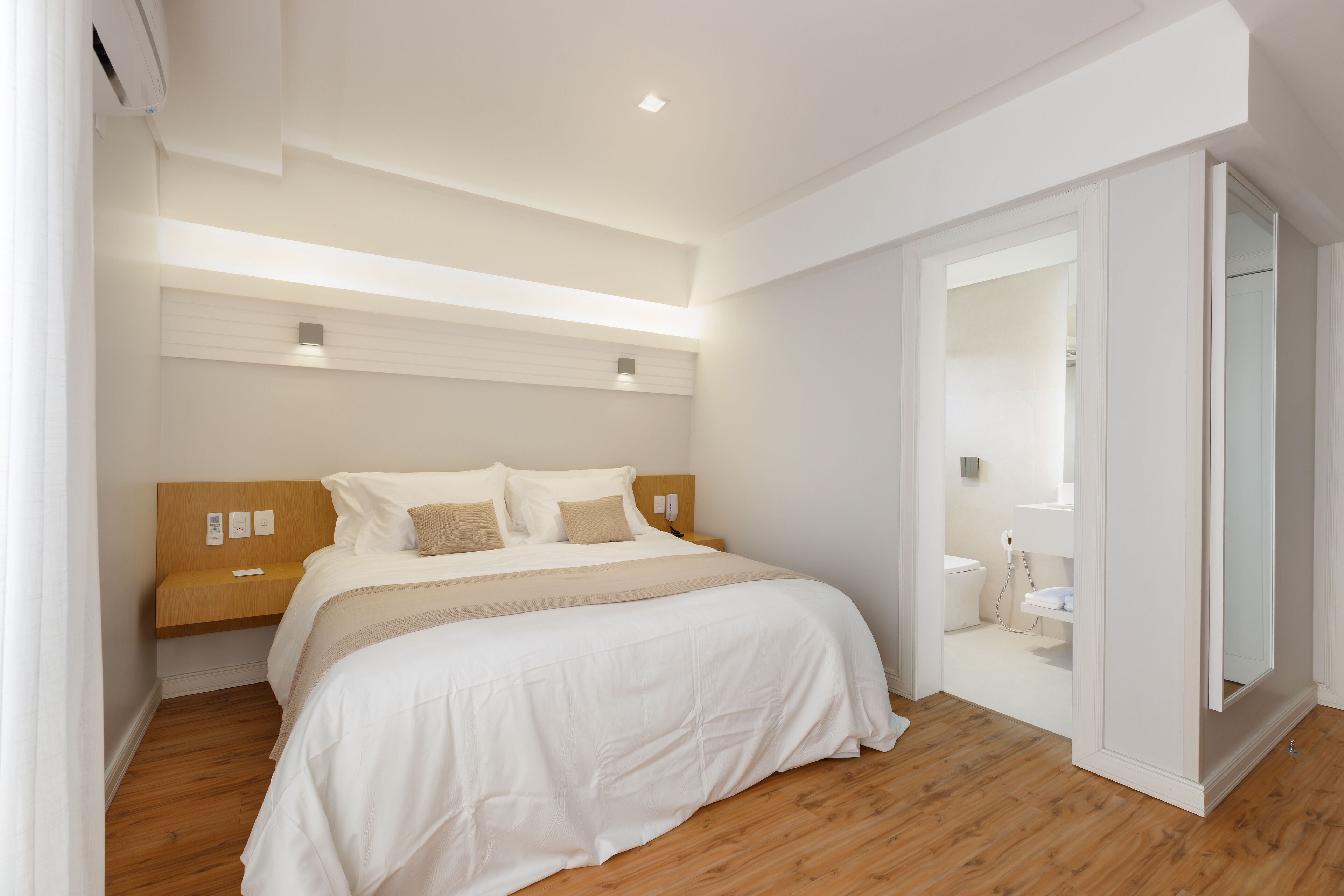 A modern bedroom with a large bed, wooden headboard, and a small bedside table.
