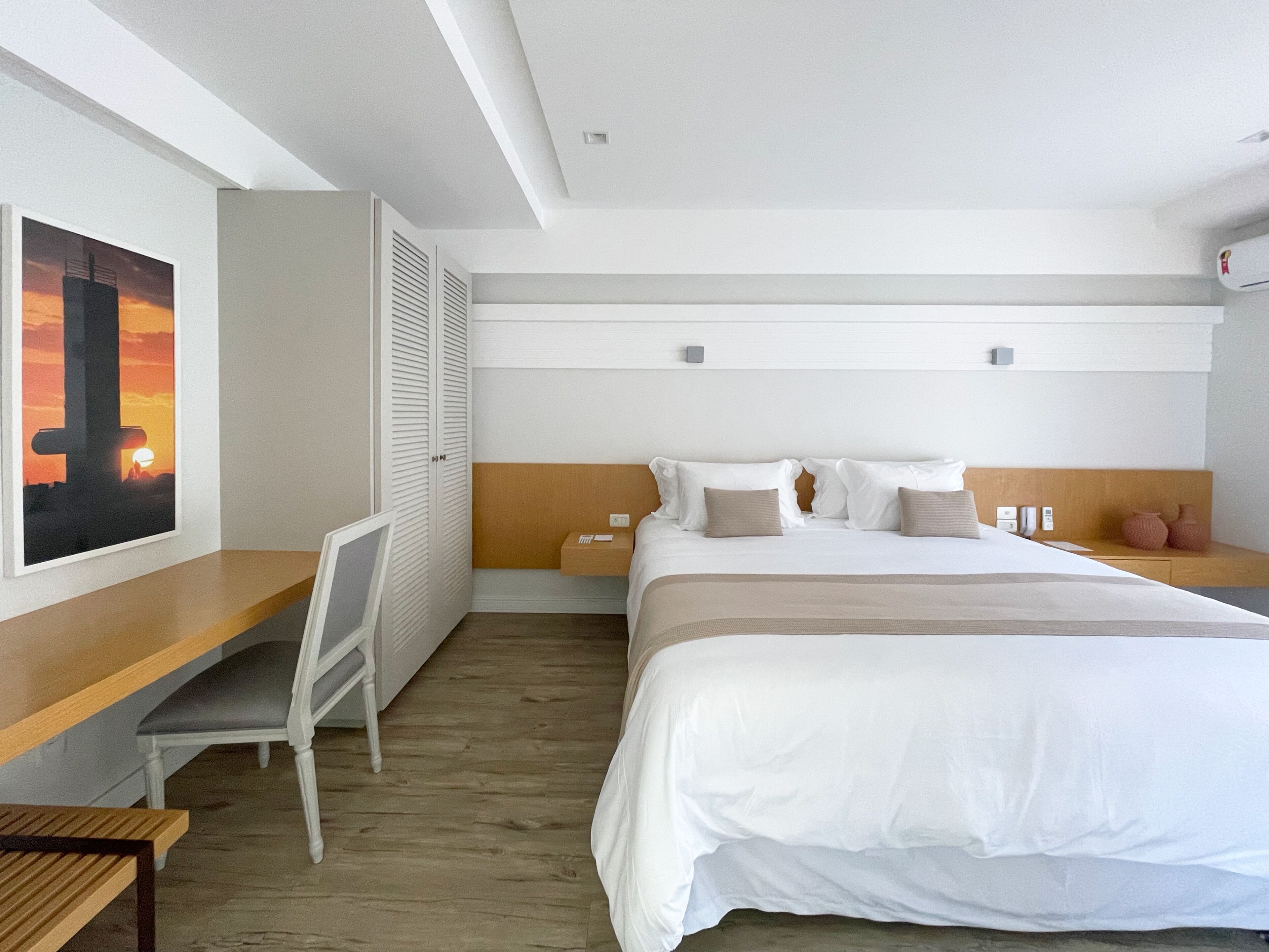 Una habitación de hotel con cama, mesitas de noche, escritorio y silla.