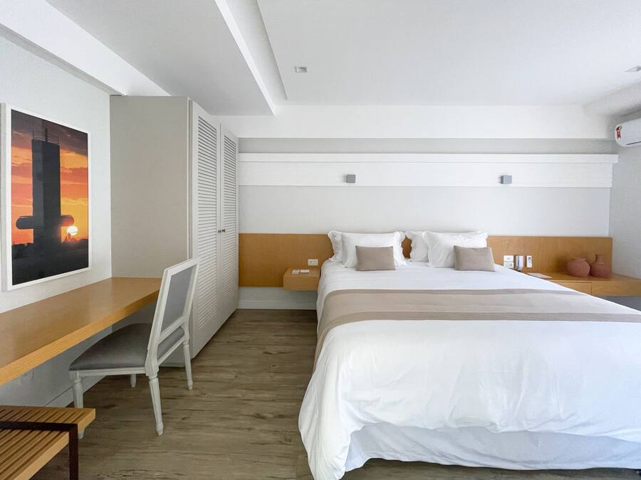 Una habitación de hotel con cama, mesitas de noche, escritorio y silla.