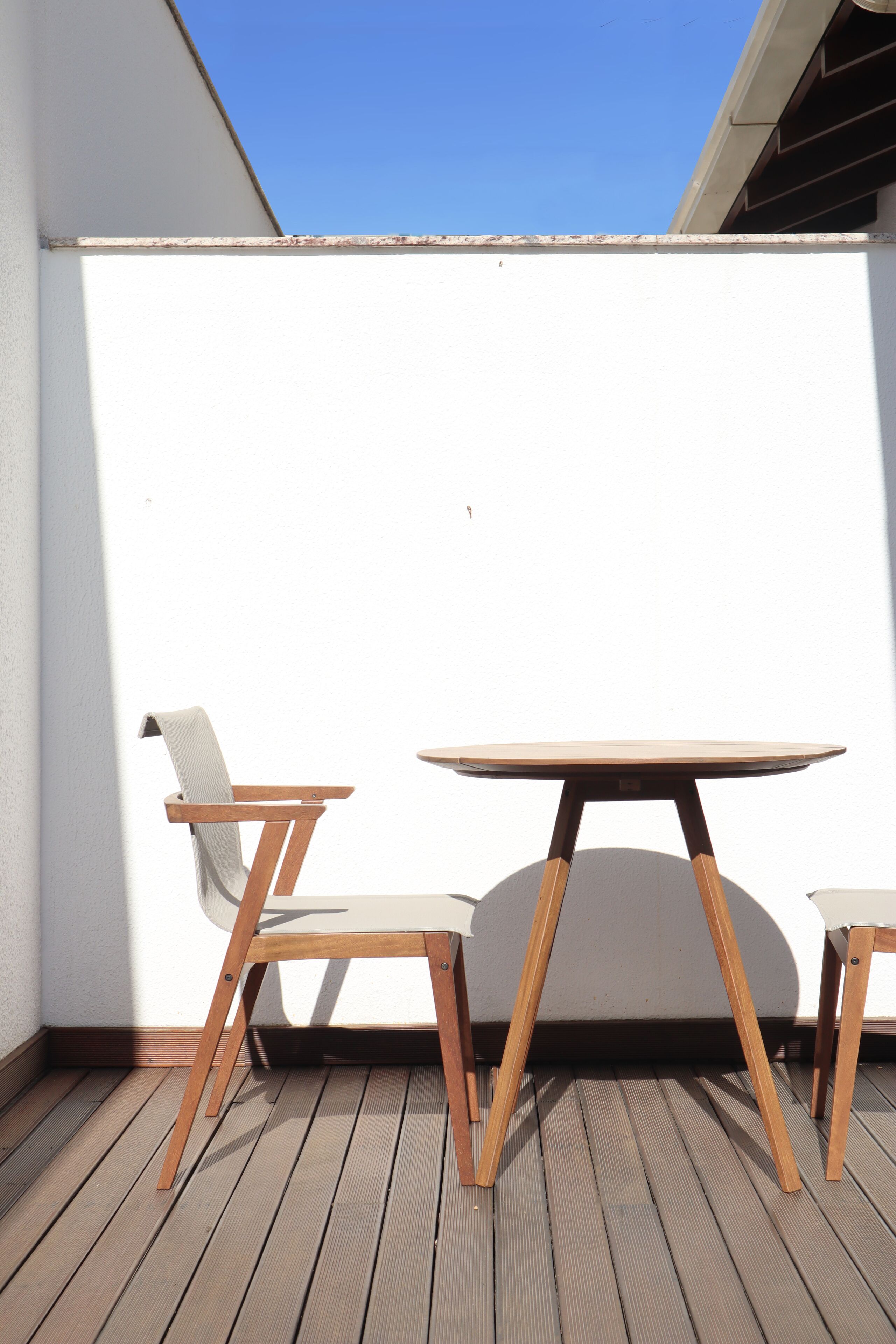 A wooden deck with a round table and two chairs.