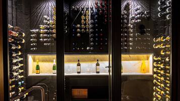 A wine cellar with multiple racks of wine bottles, a glass cabinet with bottles, and a wooden sign labeled "QUINTA DA CAVOSA".
