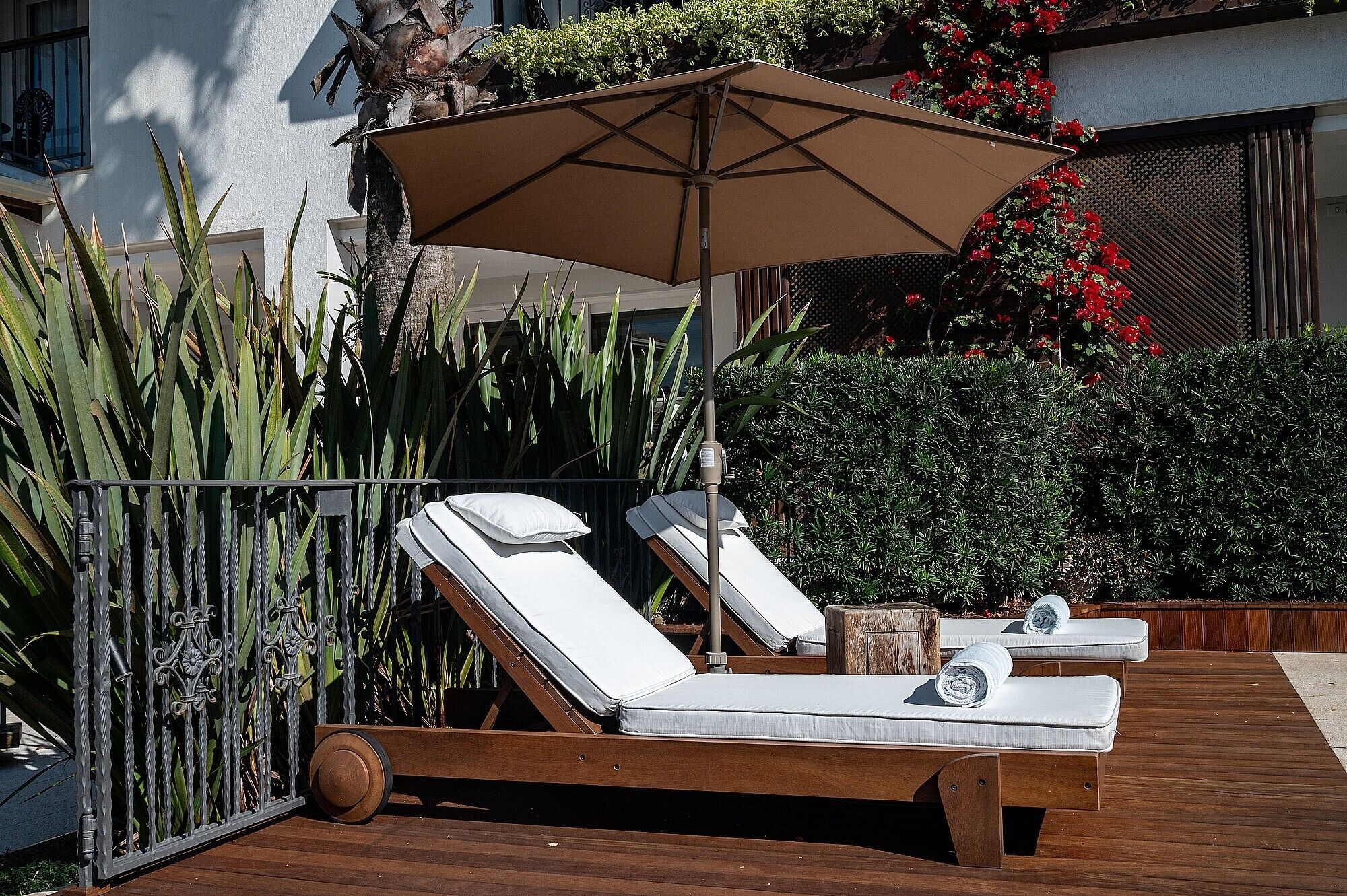 Een houten terras met twee ligstoelen en een grote parasol.