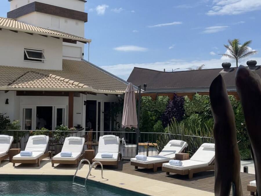 A pool area with lounge chairs and a building with a tiled roof in the background.