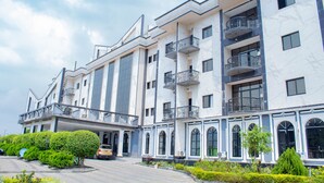 A multi-story hotel with balconies, large windows, and a landscaped front yard. - Marcsons Hotels and Resorts (Limbe)