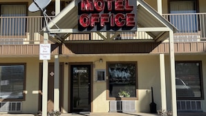 A motel office with a sign, a parking sign, and a door labeled "OFFICE".