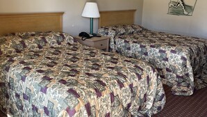 A hotel room with two beds, a nightstand, a lamp, and a wall with decorative elements.