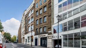 A multi-story building with a storefront labeled "Optelma." - Mulberry House London by City Living London (London)