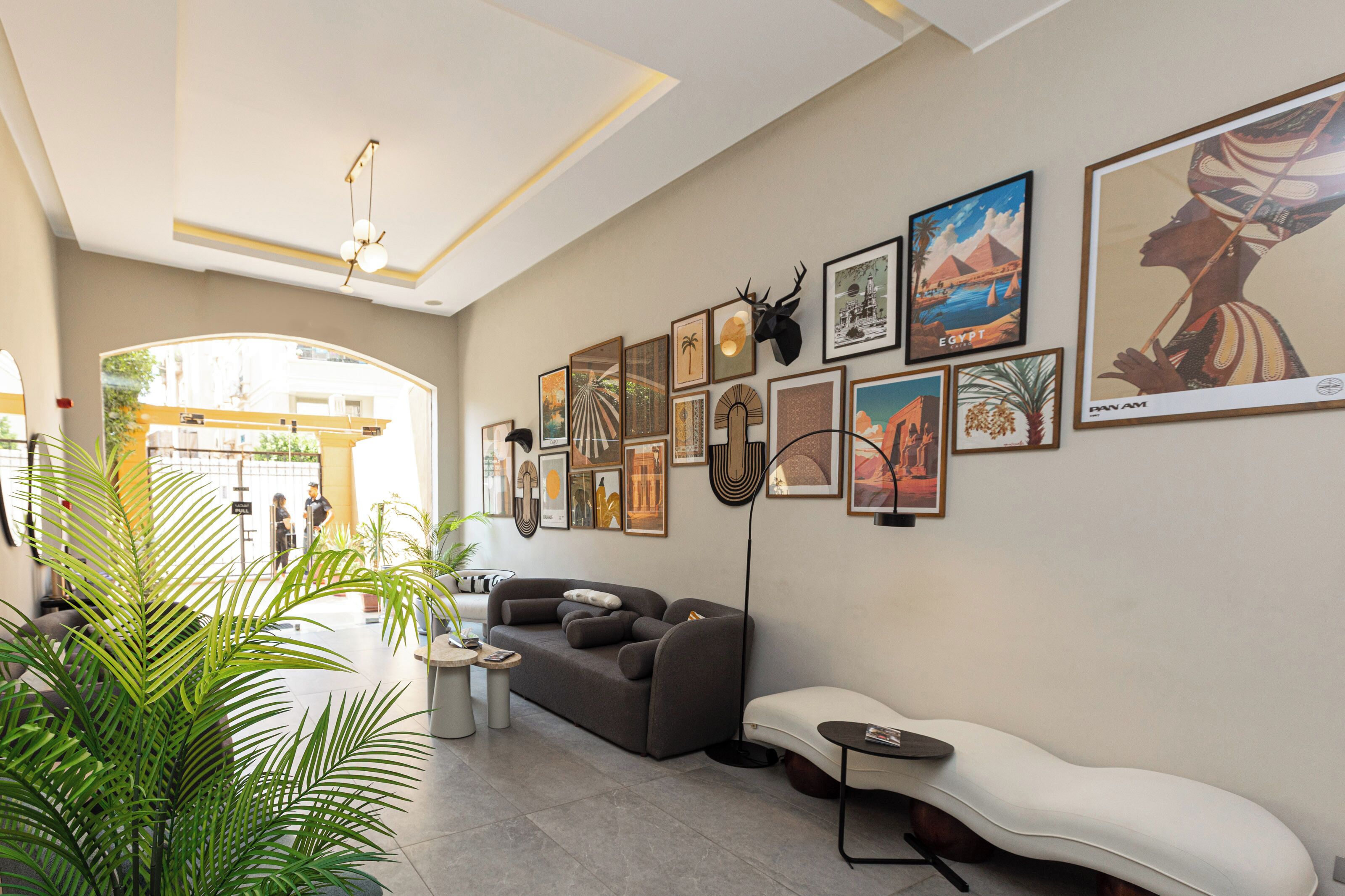 A modern interior with a sofa, a white bench, and a wall adorned with framed artwork.