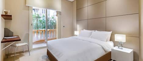 A modern bedroom with a large bed, a desk, and a nightstand.