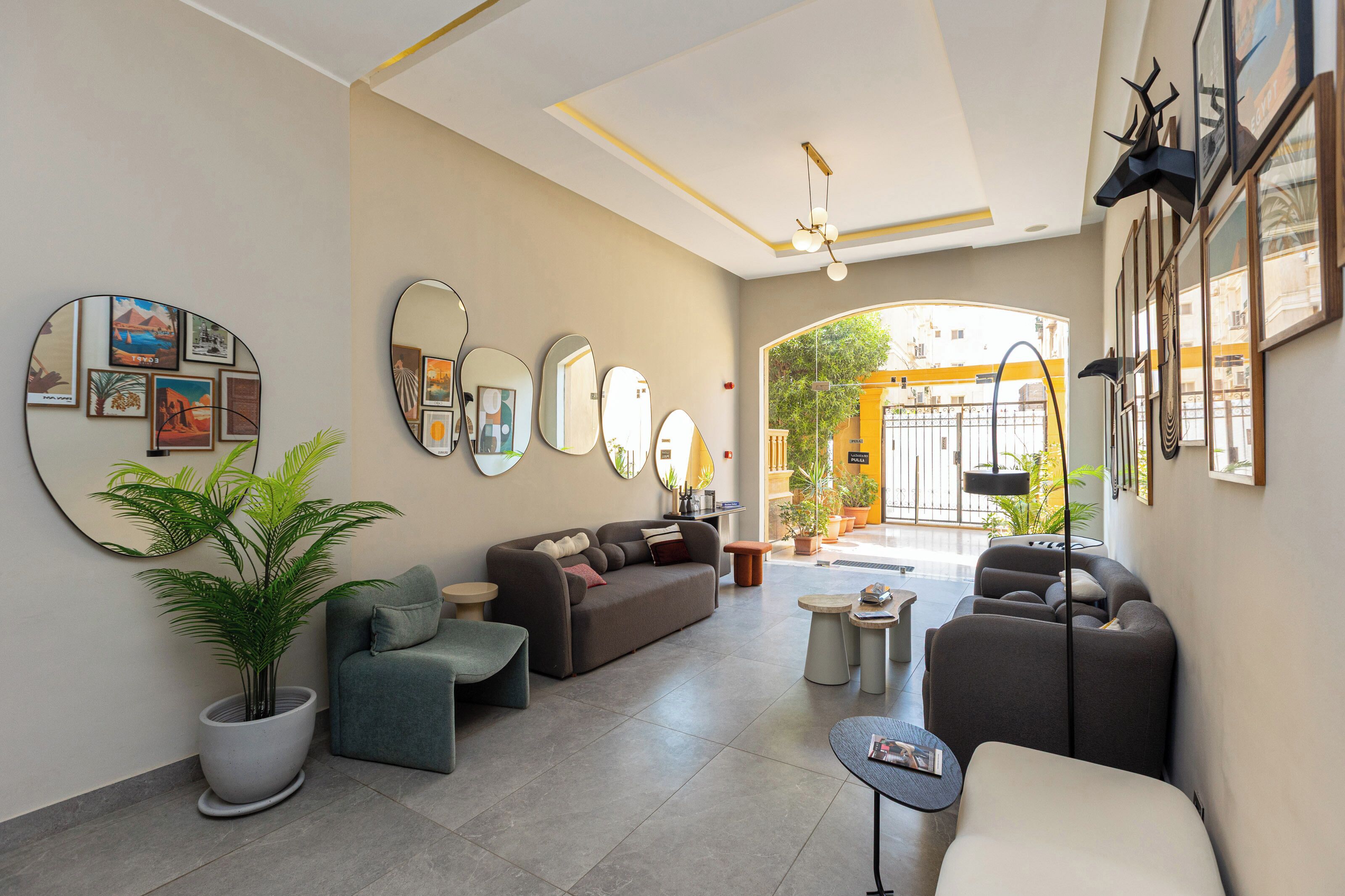 A modern living room with a sofa, armchairs, a coffee table, and a potted plant.