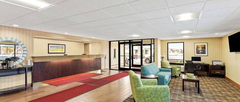 A hotel lobby with a reception desk, seating area, and a large window.