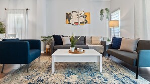Un salon moderne avec une table basse blanche, deux canapés et un tapis à motifs.