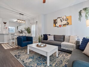 Una sala de estar moderna con un sofá, una mesa de centro y un comedor con una mesa y sillas.