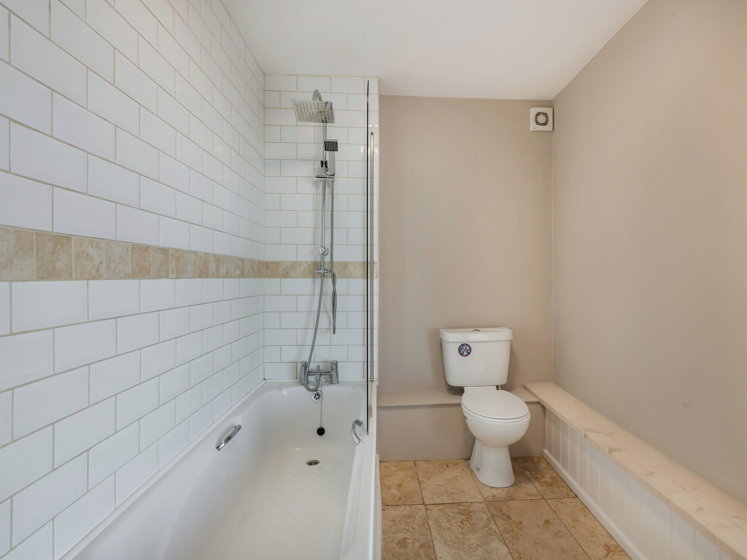 A bathroom with a bathtub, toilet, and shower.